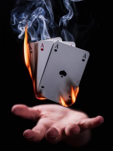man holding cards in fire above his hands