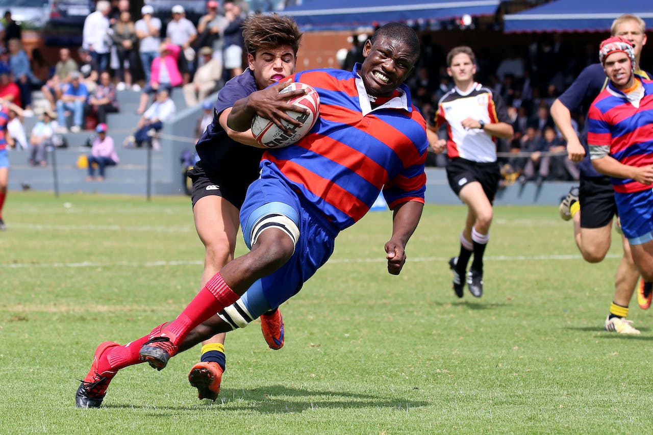 Group of Men Playing Rugby on Grass Field